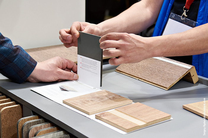 Kundenberatung im Fachhandel: Zwei Personen begutachten verschiedene Materialmuster für Bodenbeläge.